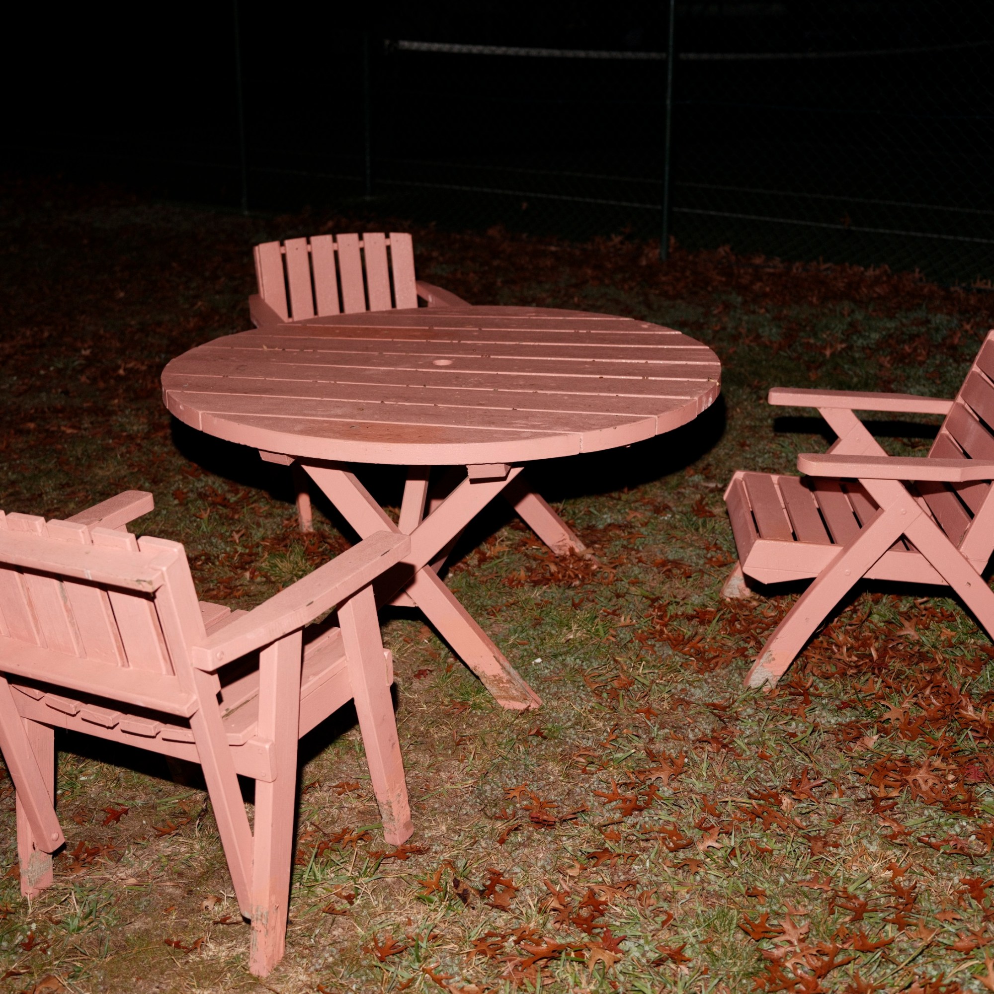 A pink outdoor table and three chairs arranged around the table